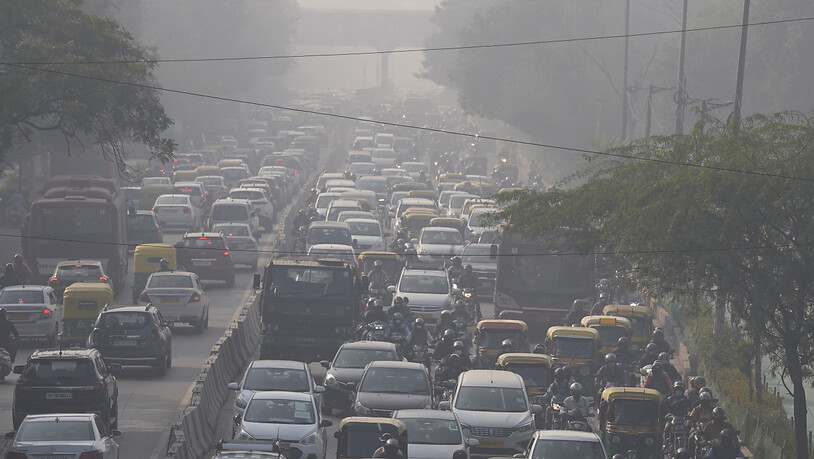 Pendler fahren inmitten von morgendlichem Dunst und giftigem Smog. Foto: Manish Swarup/AP/dpa