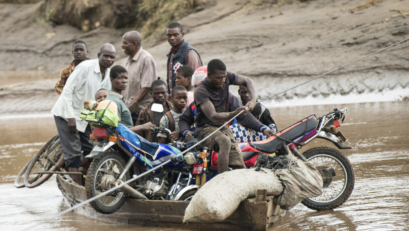 dpatopbilder - Männer transportieren ihre geretteten Habseligkeiten mit einem Holzboot. Foto: Thoko Chikondi/AP