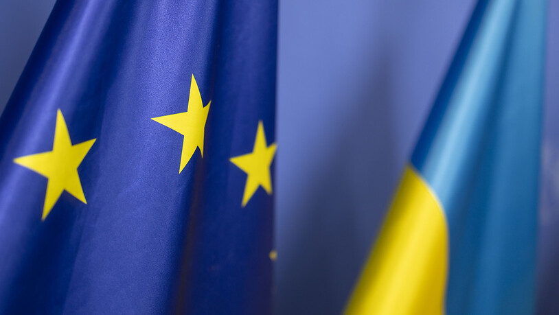 ARCHIV - Die Fahne der Ukraine steht vor der Flagge der europäischen Union. Die EU-Staaten wollen der Ukraine in den kommenden zwölf Monaten eine Million neue Artilleriegeschosse für den Kampf gegen Russland liefern. Foto: Christoph Reichwein/dpa