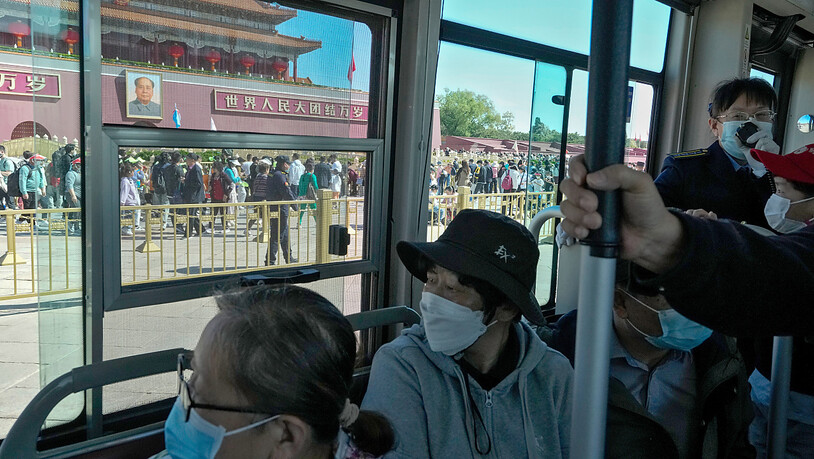Pendler mit Gesichtsmasken in einem Bus in Peking. Foto: Andy Wong/AP/dpa