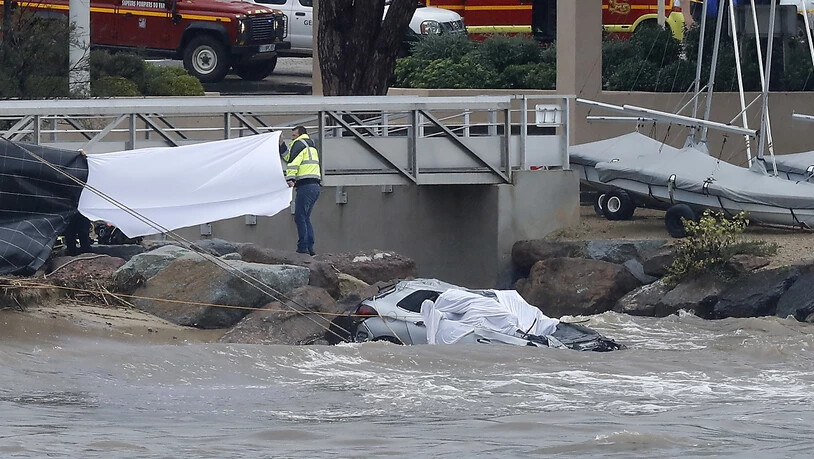 Rettungskräfte bergen die Leichen von zwei Menschen aus einem Auto, das von einem über die Ufer getretenen Fluss mit ins Meer gerissen wurde.