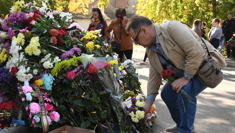 Ein Mann legt an der Schule Blumen für die Opfer nieder.