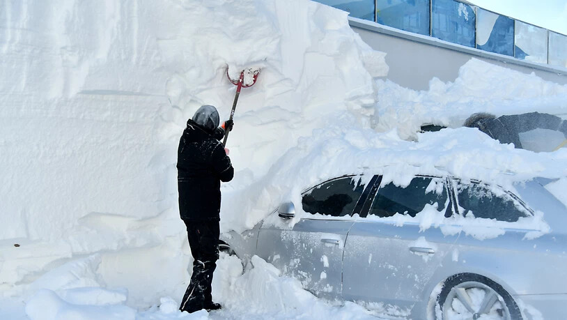 Ein Mann befreit ein schwer eingeschneites Auto von der Schneelast in Obertauern (AUT).
