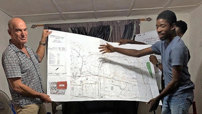 Walz und Bob studieren in Liberia Pläne für ein Abwassersystem. 