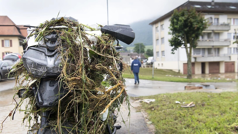 Ein von mitgerissenen Pflanzen verschmutzes Motorrad in Dombresson.
