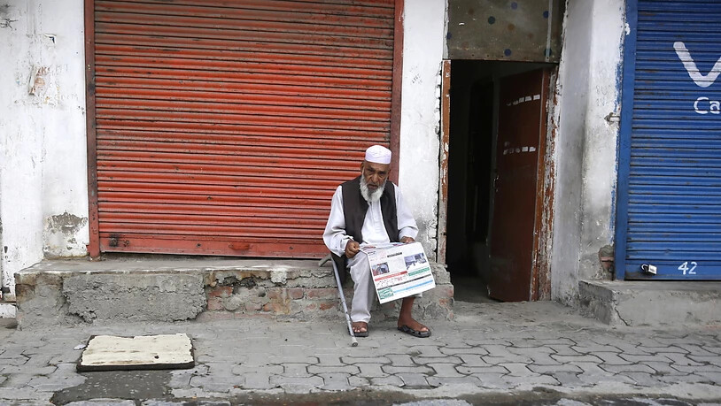 Ausgangssperre in Srinagar: Ein Mann liest vor einem geschlossenen Geschäft in der Sommerhauptstadt von Jammu und Kashmir eine Zeitung.