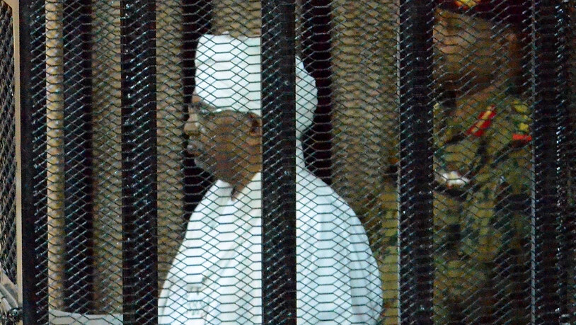 Der in eine weisse sudanesische Robe gekleidete angeklagte frühere Machthaber Sudans, Omar al-Baschir, verfolgt den Prozess aus einem Gitterkäfig im Gerichtssaal.