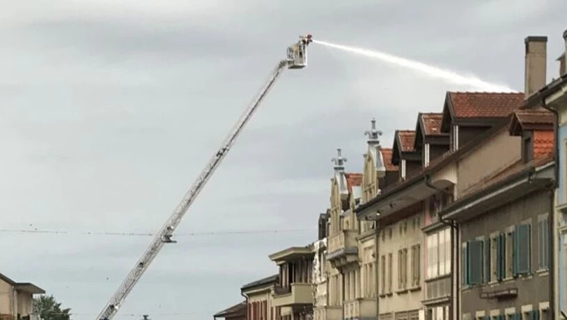 Ein Feuerwehrmann bekämpft von einer Drehleiter aus den Dachstockbrand.
