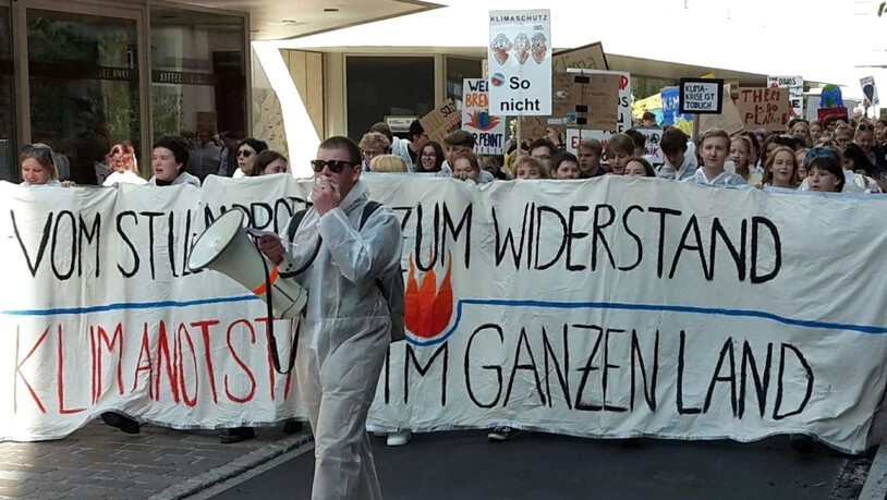 Klima-Alarm in St. Gallen - demonstrierende Schülerinnen und Schüler in weissen Schutzanzügen ziehen durch die Innenstadt.