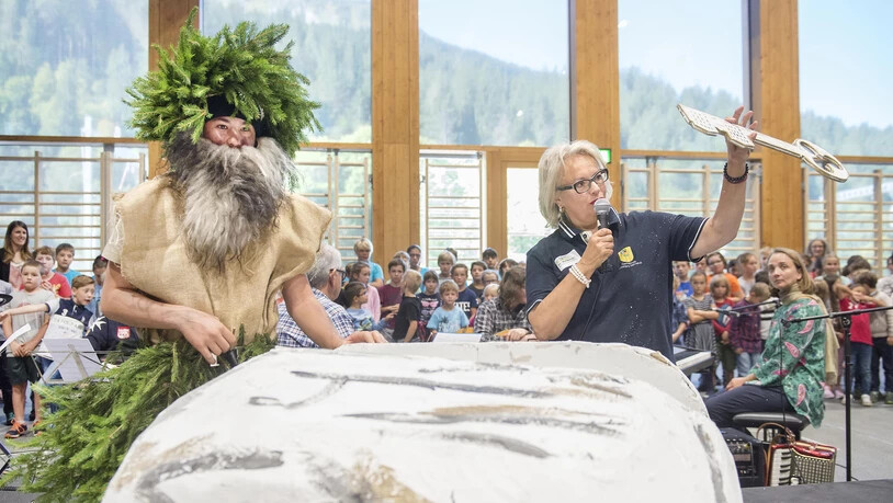An der Eröffnung der Schulanlage in Klosters überbringt das Wildmannli  Schulratspräsidentin Eva Waldburger den Schlüssel.