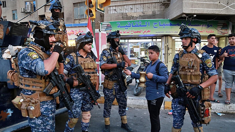 Ein Strassenverkäufer im Stadtteil Sadr City von Bagdad verkauft der Polizei Kaffee. Iraks Regierungschef Adel Abdel Mahdi hatte am Montag die Armee aus dem Stadtteil abgezogen und sie durch Polizisten ersetzt.