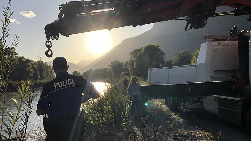 Walliser Kantonspolizisten bei der Bergung des Autowracks aus der Rhone. Nun steht fest, dass im Auto ein Mann und ein Mädchen gesessen hatten, die seit einem Unwetter vermisst werden.