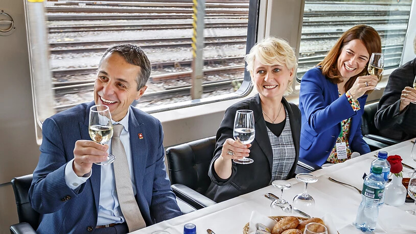 Isabelle Moret (Bildmitte), Bundesrat Ignazio Cassis und FDP-Parteipräsidentin Petra Gössi prosten im Zug den anderen Gästen zu, welche zur Wahlfeier ins Waadtland mitreisen.