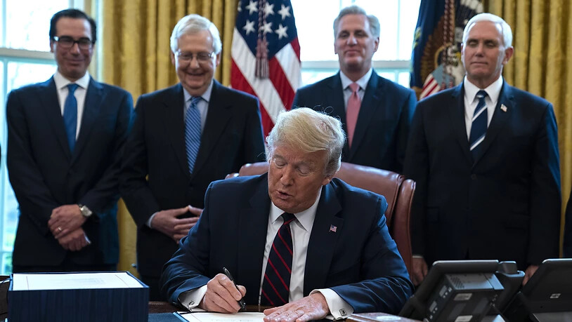 US-Präsident Donald Trump (Mitte) unterzeichnet im Oval Office des Weissen Hauses das Konjunkturpaket, mit dem rund 2 Billionen US-Dollar in die Wirtschaft gepumpt werden sollen.