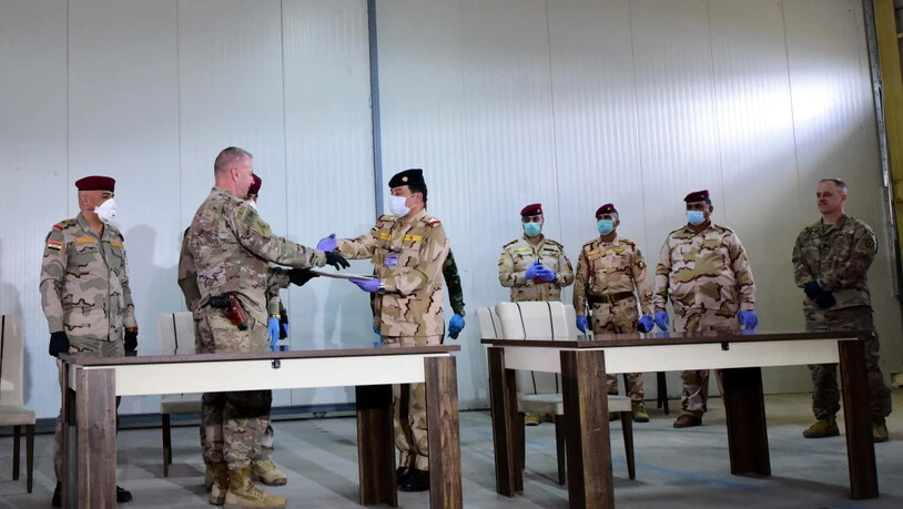 US-Brigadegeneral Vincent Barker (2. links) gibt einem irakischen General bei der Übergabe der Basis K1 an den Irak die Hand. Die von den USA geführte Militärkoalition zog sich am Sonntag von der dritten Basis im Irak zurück.