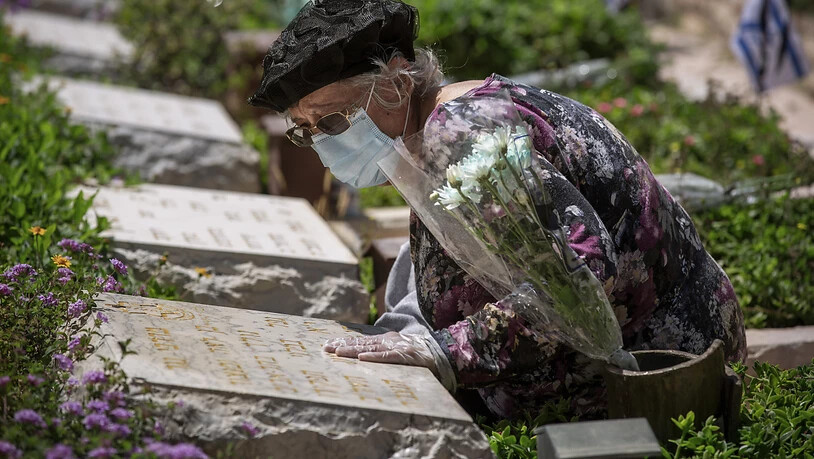 Eine Frau mit Schutzmaske und Handschuhen am Grab ihres Bruders: Israel gedenkt inmitten der Corona-Krise seiner getöteten Soldaten und Terroropfer.
