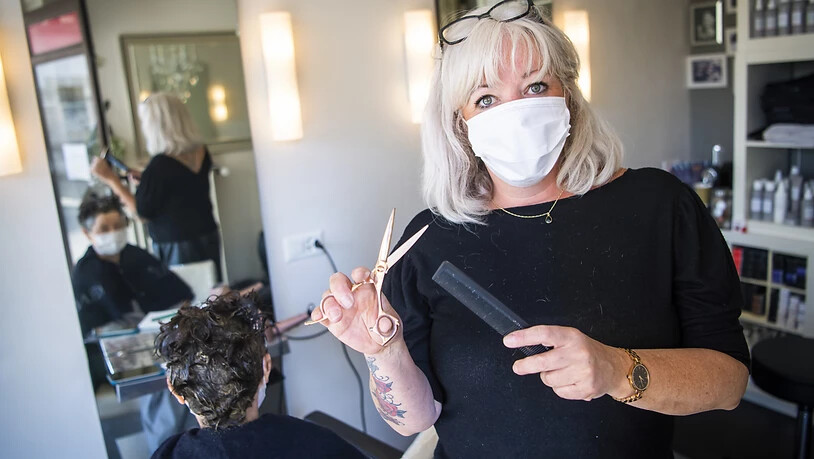Die Lausanner Coiffeuse Sonia Cottini an der Arbeit: Die Gesichtsmasken seien störend, aber sie werde sich daran gewöhnen müssen, sagt sie.