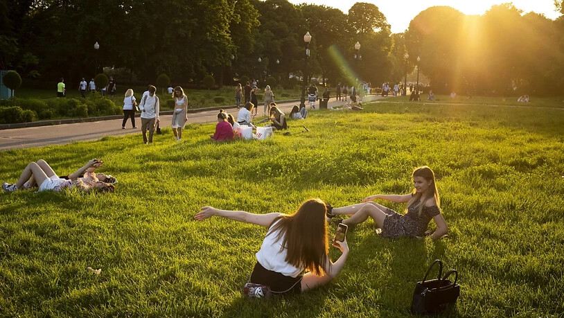 Menschen genießen das warme Wetter im Gorki-Park während des Sonnenuntergangs. Die Behörden in Moskau haben die Ende März wegen des Ausbruchs des Coronavirus eingeführten strengen Sperrmaßnahmen gelockert. Foto: Alexander Zemlianichenko/AP/dpa