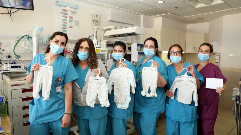 HANDOUT - Krankenschwestern der Säuglingsstation zeigen gespendete Babykleidung und Strampelanzüge. Aus Armut hat eine Israelin vor zwölf Jahren nach der Geburt ihres Kindes in einem Krankenhaus in der Hafenstadt Haifa Babykleidung mitgehen lassen. Foto:…