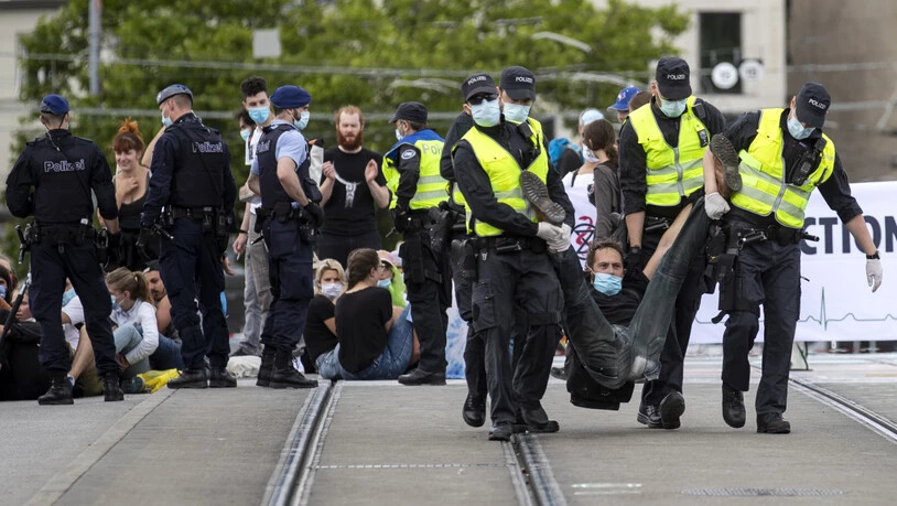 Polizisten tragen einen Aktivisten der Umweltbewegung Extinction Rebellion von der Quaibrücke in Zürich.