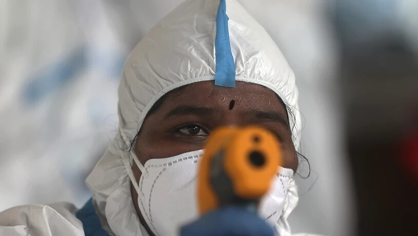 Eine medizinische Mitarbeiterin überprüft im indischen Mumbai die Temperatur einer Frau. Foto: Rafiq Maqbool/AP/dpa
