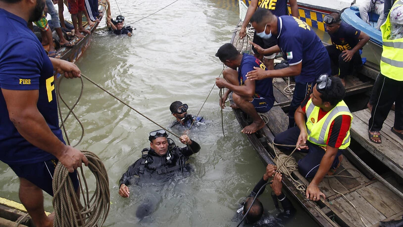 Taucher steigen nach einem Schiffsunglück für die Bergung von Opfern in den Fluss Buriganga. Foto: Str/Xinhua/dpa