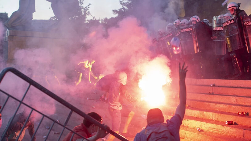Demonstranten und Polizisten treffen auf den Stufen des Parlamentsgebäudes in Belgrad aufeinander. Die Demonstranten protestieren gegen geplante drastische Massnahmen zur Eindämmung der Corona-Pandemie in Serbien. (Foto: Marko Drobnjakovic/AP/KEYSTONE…