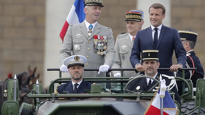 Emmanuel Macron (r), Präsident von Frankreich, und der Generalstabschef der französischen Armeen, General Francois Lecointre stehen im Kommandowagen, während der Militärparade zum französischen Nationalfeiertag. Foto: Christophe Ena/AP/dpa