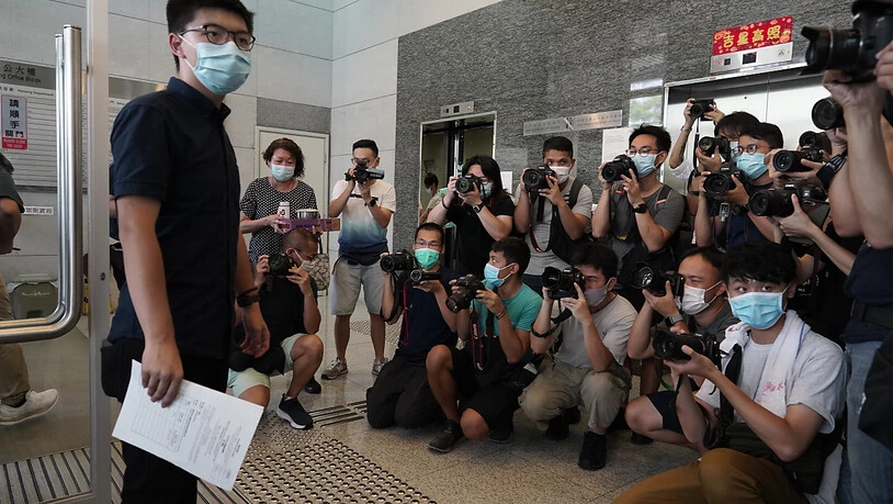 Der pro-demokratische Aktivist Joshua Wong (l) zeigt Journalisten die Nominierungsunterlagen, während er seine Kandidatur für die im September in Hongkong stattfindenden Wahlen zum Legislativrat einreicht. Foto: Vincent Yu/AP/dpa