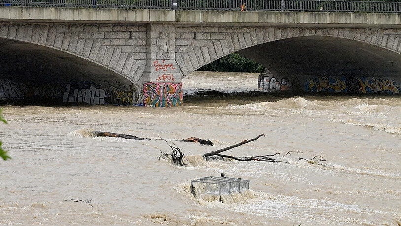 Braunes Wasser fließt nach starken Regenfällen unter der Reichenbachbrücke durch das Flussbett der Isar in München. Foto: Peter Kneffel/dpa