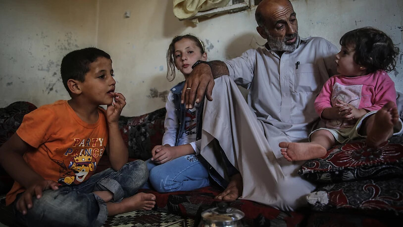 Der Lebensmittelverkäufer Khaled Amash spricht mit seinen Kindern in seinem neuen Haus. Das alte Haus von Amash wurde nach einem Bombenangriff durch regimetreue Kräfte zerstört. Foto: Anas Alkharboutli/dpa