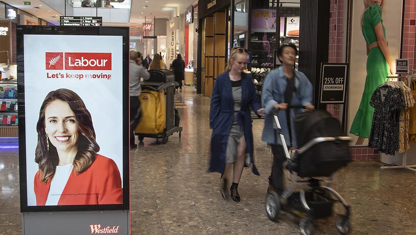 Menschen gehen in einem Einkaufszentrum an einer elektronischen Plakatwand vorbei, die ein Foto der neuseeländischen Premierministerin Jacinda Ardern zeigt. Neuseeländer gehen bei den Parlamentswahlen am Samstag, den 17.10.2020, an die Urnen. Foto: Mark…