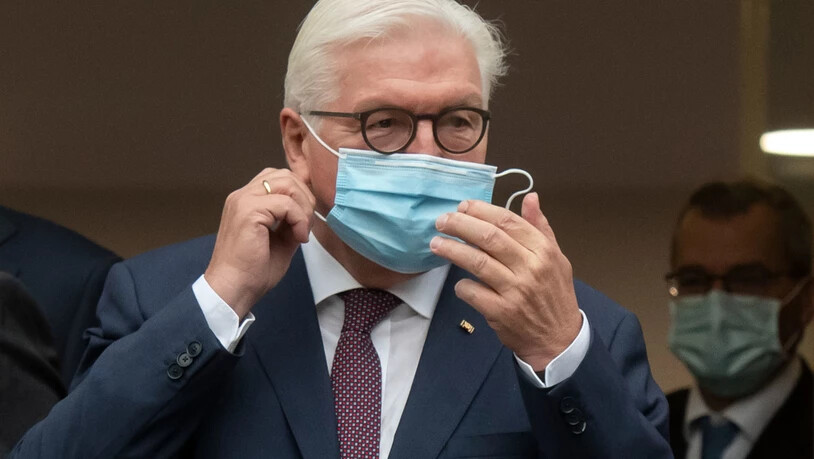ARCHIV - Bundespräsident Frank-Walter Steinmeier steht vor einem Gebäude der Uniklinik und nimmt für ein Gruppenfoto seine Maske ab. Foto: Bernd Thissen/dpa
