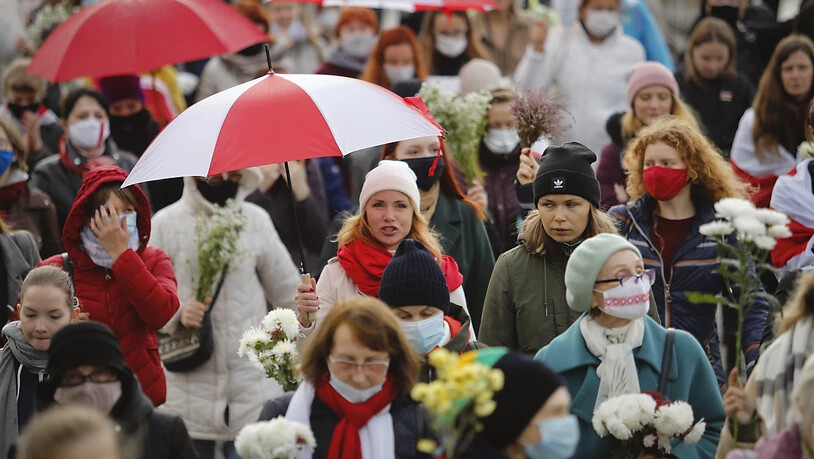 Belarussische Frauen mit Regenschirmen in den Farben der alten belarussischen Nationalflagge. Foto: -/AP/dpa