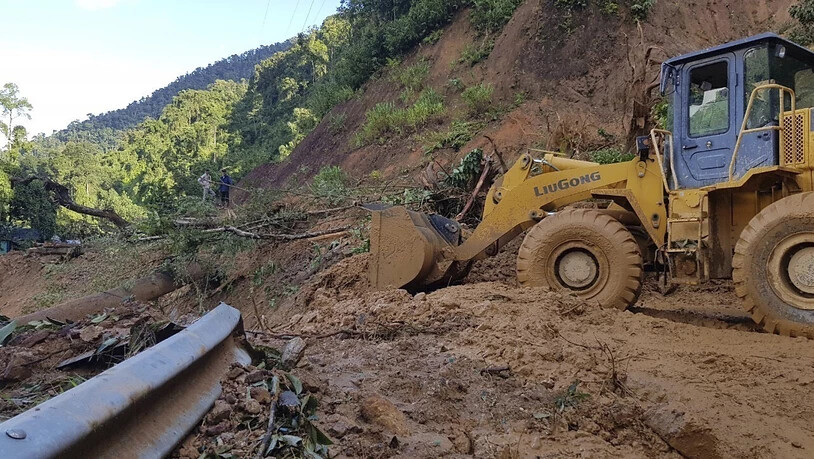 Ein Bulldozer räumt eine durch einen Erdrutsch beschädigte Straße. Zwei durch den Taifun «Molave» verursachte Erdrutsche haben in Vietnam mindestens 13 Menschen getötet. Foto: Bui Van Lanh/VNA/dpa