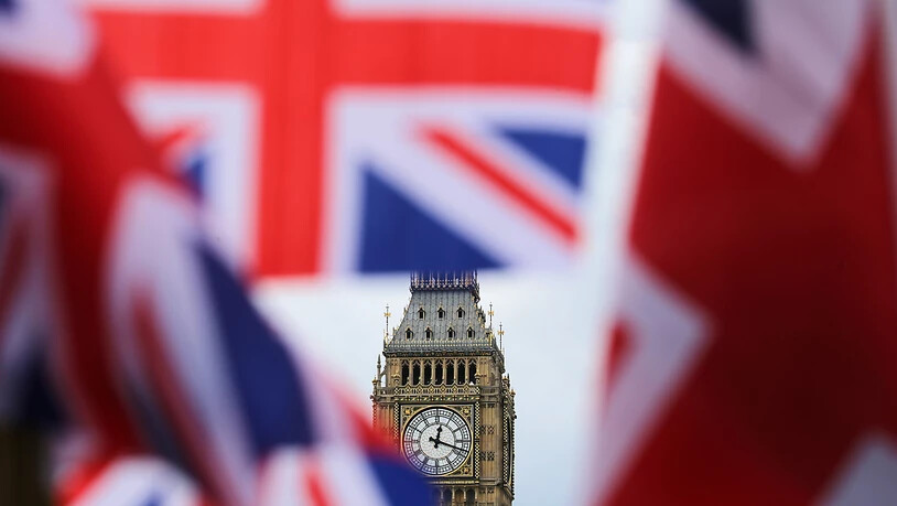ARCHIV - Britische Fahnen wehen vor dem berühmten Uhrturm Big Ben. Das britische Parlament stimmt am Mittwoch (30.12.2020) über den Brexit-Handelspakt mit der Europäischen Union ab. Beide Kammern sollen die Vereinbarung innerhalb weniger Stunden abnicken…