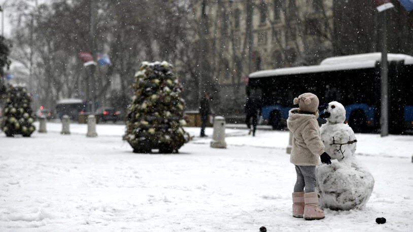 Ein Mädchen spielt mit einem Schneemann auf der Straße in Madrid. Das Sturmtief «Filomena» sorgt im Sonnenland Spanien für Rekordkälte, viel Schnee und einiges Chaos. Foto: Óscar Cañas/EUROPA PRESS/dpa