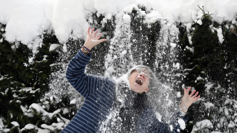 Ein junger Mann nimmt am Freitag im verschneiten Zürich eine "Schneedusche".