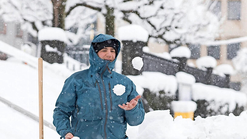 In Glarus jongliert ein Mann vor der Stadtkirche mit Schneebällen.