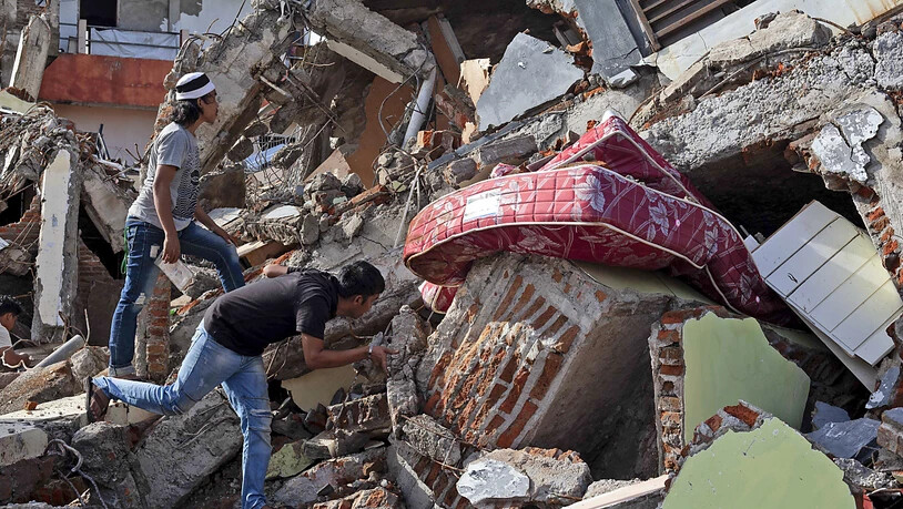 Anwohner inspizieren ein Gebäude, das bei einem Erdbeben eingestürzt ist. Foto: Yusuf Wahil/AP/dpa
