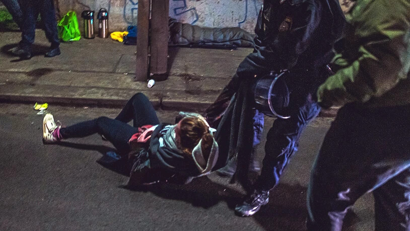 Ein Polizist zerrt eine Demonstrantin von der Straße. Foto: Christopher Glanzl/APA/dpa