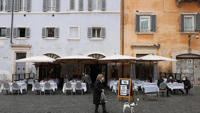 Eine Frau geht inmitten der Corona-Pandemie mit ihrem Hund an einem kürzlich wiedereröffneten Restaurant in der  Innenstadt Roms vorbei. Foto: Vincenzo Livieri/ZUMA Wire/dpa