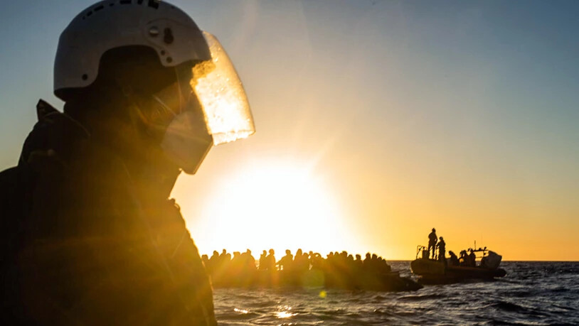 HANDOUT - Ein Mitarbeiter des Seenotrettungsschiffs «Ocean Viking» beobachtet ein mit Migranten überfülltes großes Schlauchboot in der Nähe der «Ocean Viking» (nicht im Bild). Foto: Hippolyte/SOS Mediterranee/dpa - ACHTUNG: Nur zur redaktionellen…