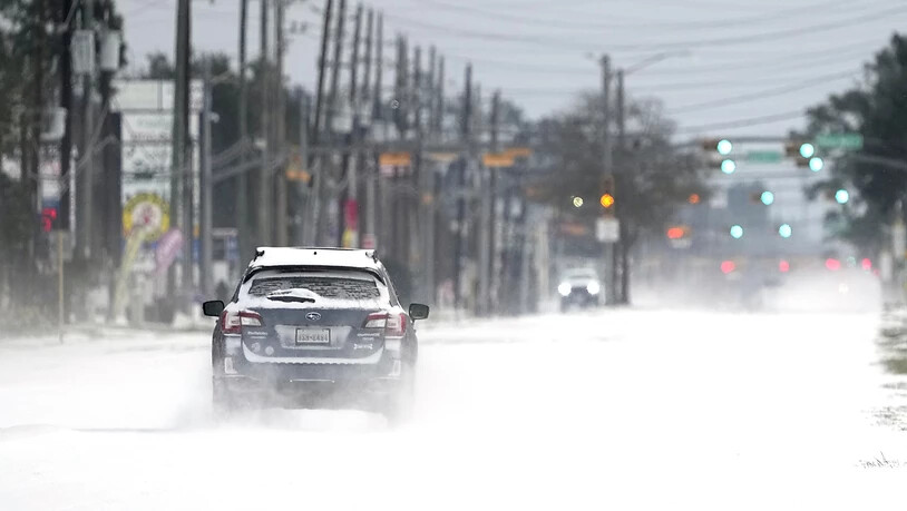 Ein Auto fährt auf einer zugeschneiten Straße. Im südlichen US-Bundesstaat Texas sind wegen ungewöhnlich kalten Winterwetters Hunderttausende Menschen mindestens zeitweise ohne Strom gewesen. Foto: David J. Phillip/AP/dpa