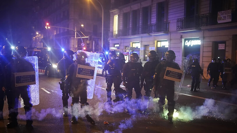 Feuerwerkskörper explodieren neben Polizisten während eines Protests gegen die Verhaftung des Rappers Pablo Hasel. Foto: Joan Mateu/AP/dpa