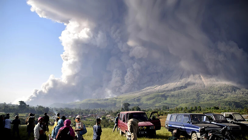 dpatopbilder - Menschen beobachten eine Eruption des Vulkans Sinabung in Karo. Foto: Uncredited/AP/dpa
