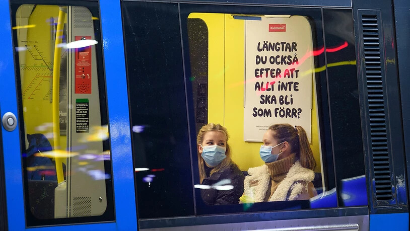 ARCHIV - Zwei Fahrgäste sitzen mit Mund-Nasen-Schutz in einer U-Bahn. Schweden hat auf die Bevölkerung gerechnet derzeit etwa dreimal so hohe Neuinfektionszahlen wie Deutschland - geplante Corona-Lockerungen dürften deshalb in dem skandinavischen Land…