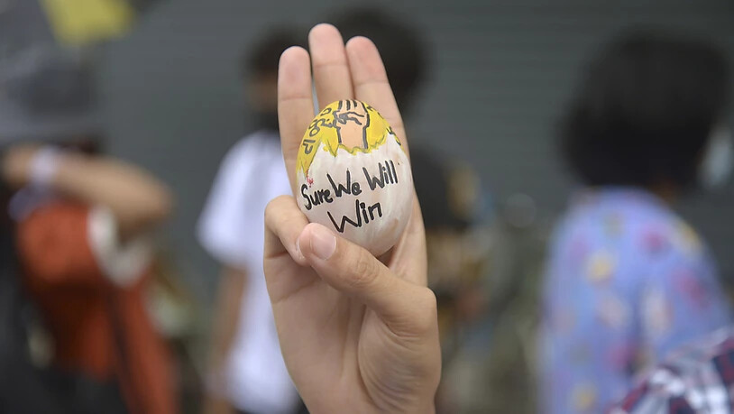 Ein Demonstrant zeigt den Drei-Finger-Gruß als Zeichen des Widerstands und hält dabei ein Osterei mit der Aufschrift "Sure we will win" (Wir werden sicher gewinnen) während eines Protestes gegen die Miltärjunta. Foto: Uncredited/AP/dpa