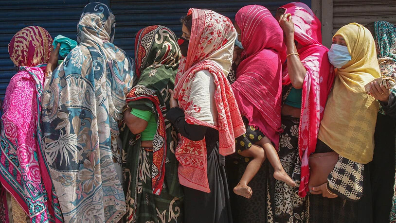 Frauen stehen gedrängt in einer Schlange, um Reis und Mehl auf dem offenen Markt zu kaufen. Ein landesweiter Lockdown hat für sieben Tage begonnen. Foto: Md Rafayat Haque Khan/ZUMA Wire/dpa