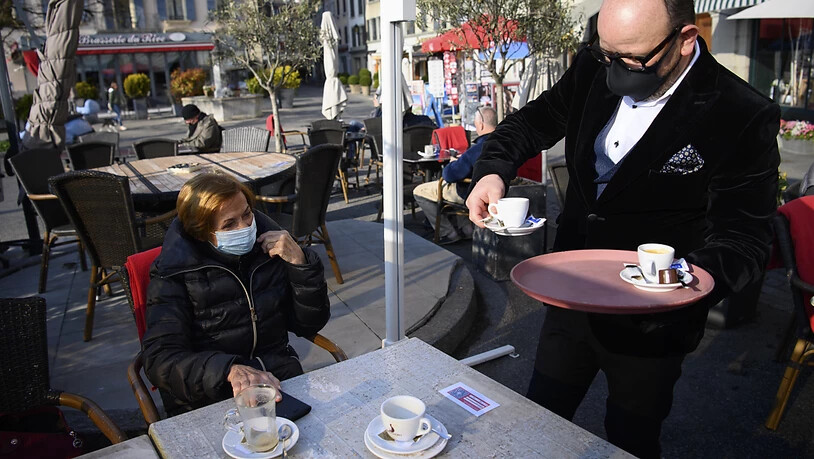 Voilà madame! - Kellner serviert maskiertem Gast den Kaffee auf der Aussenterrasse des "Restaurant Le Leman" in Nyon VD.